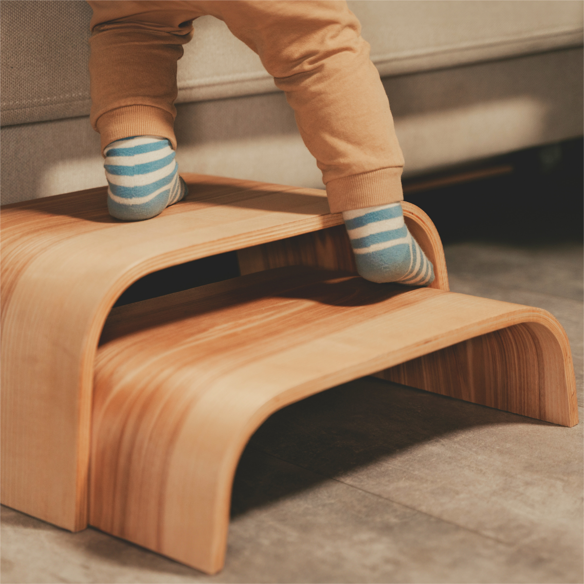 Child's feet on two stacked wooden step stools showing versatile two-in-one design