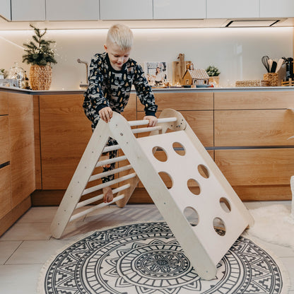 Toddler climbing on indoor gym triangle in modern kitchen