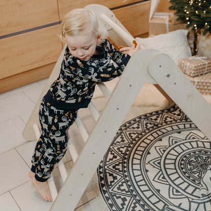 Toddler using climbing triangle as play fort with cozy interior space