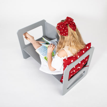 Toddler girl sitting at gray Montessori table reading book independently