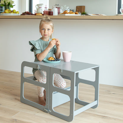 Child sitting at gray Montessori kitchen tower table with storage compartments