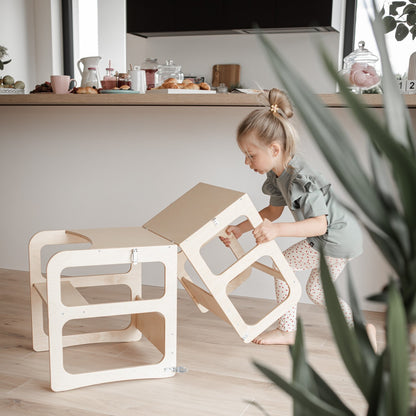 Child opening fold-down desk top on white convertible kitchen tower furniture