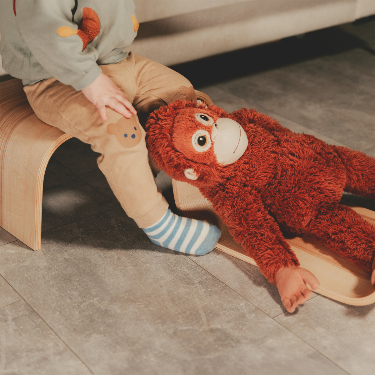 Toddler playing with toy near wooden step stool indoors