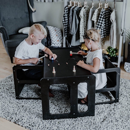 Two children playing together at black Montessori table and chairs set in playroom