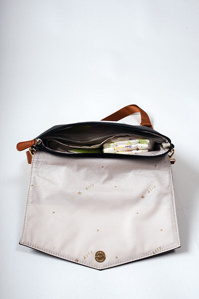 Black coffee baby handbag opened to show cream and gold interior storage compartments