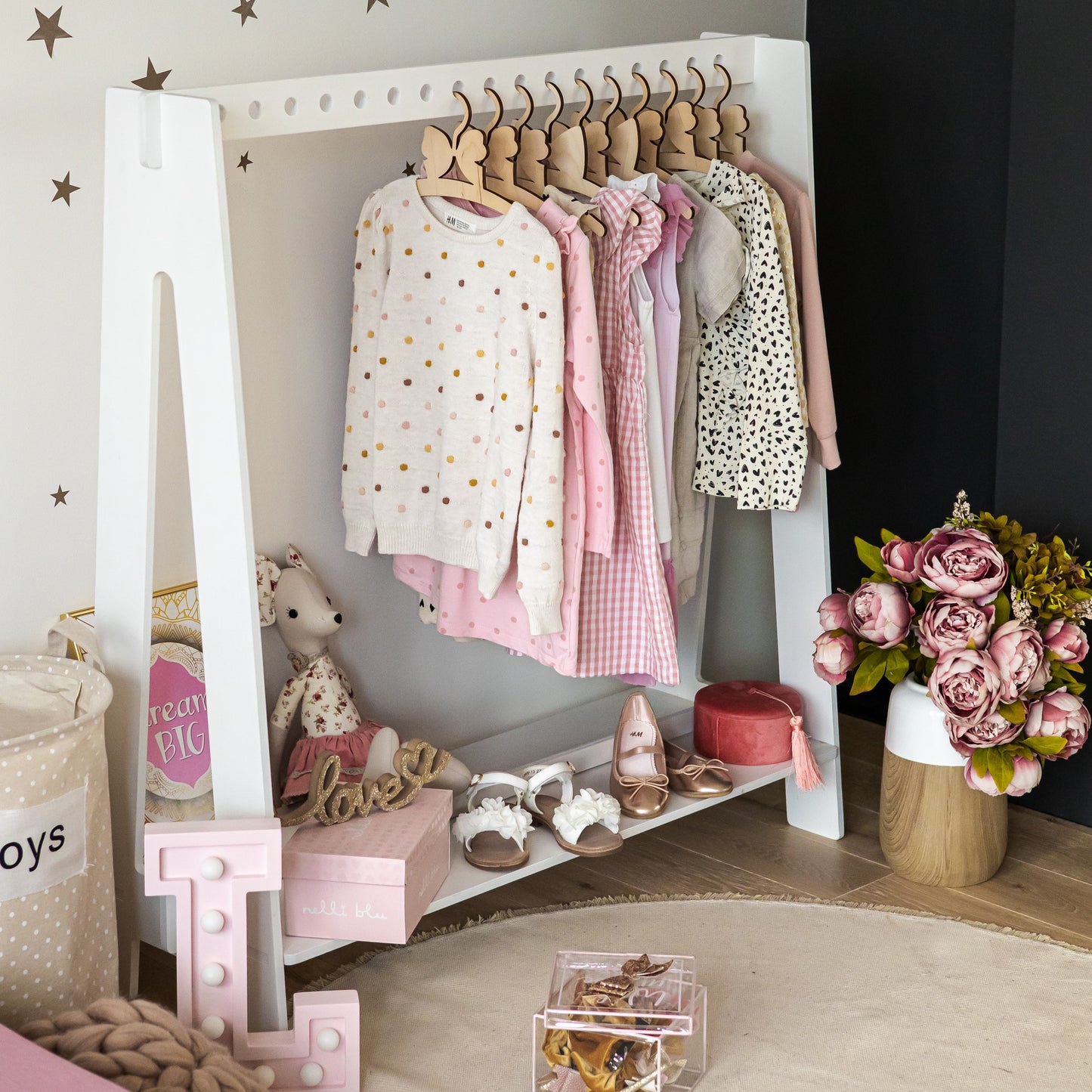 Grey Montessori clothing rack displaying pink dresses and shoes with room styling