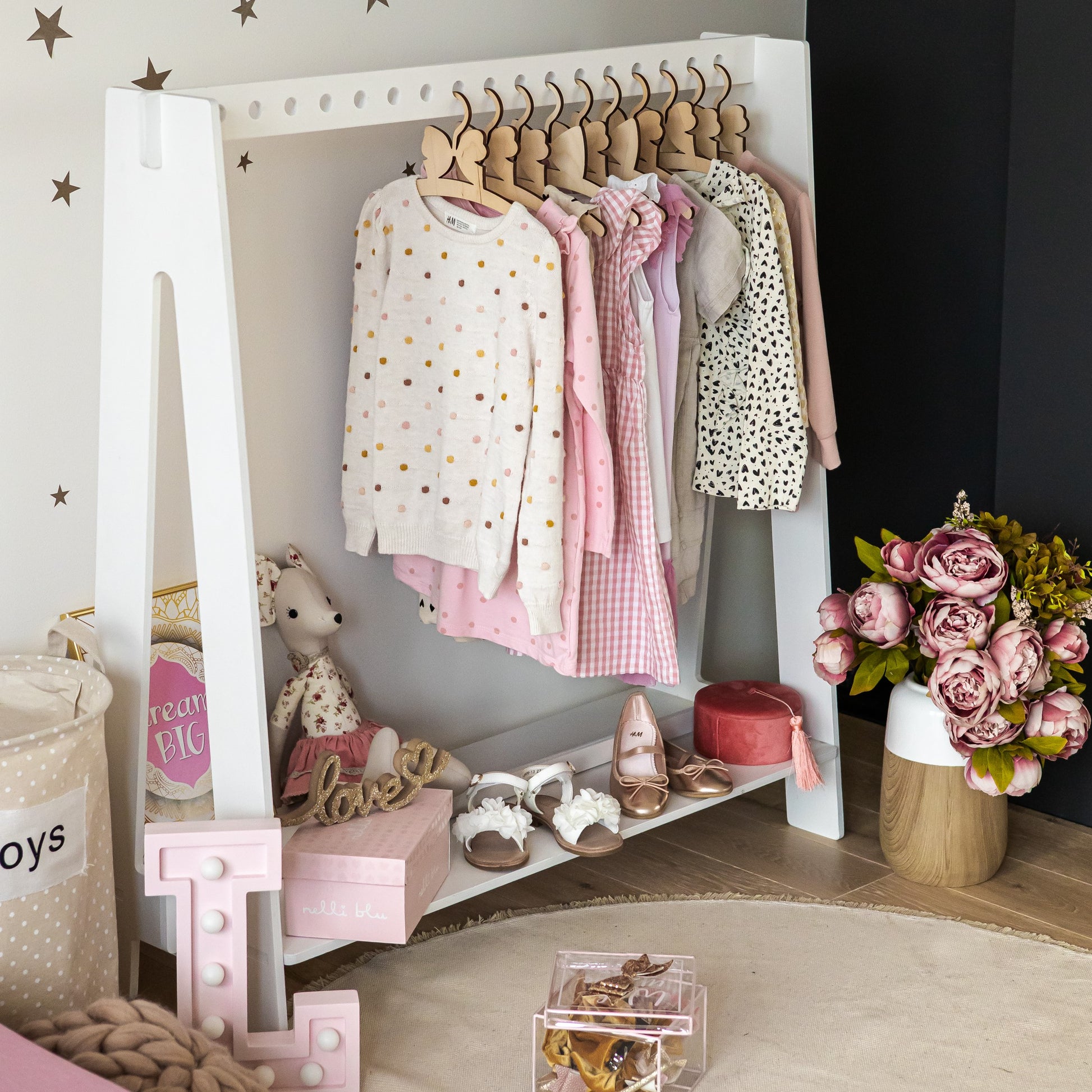 Grey Montessori clothing rack displaying pink dresses and shoes with room styling
