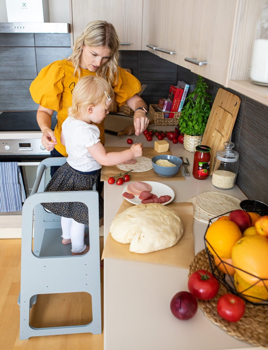 Parent and child cooking together with child on natural wood helper tower stool