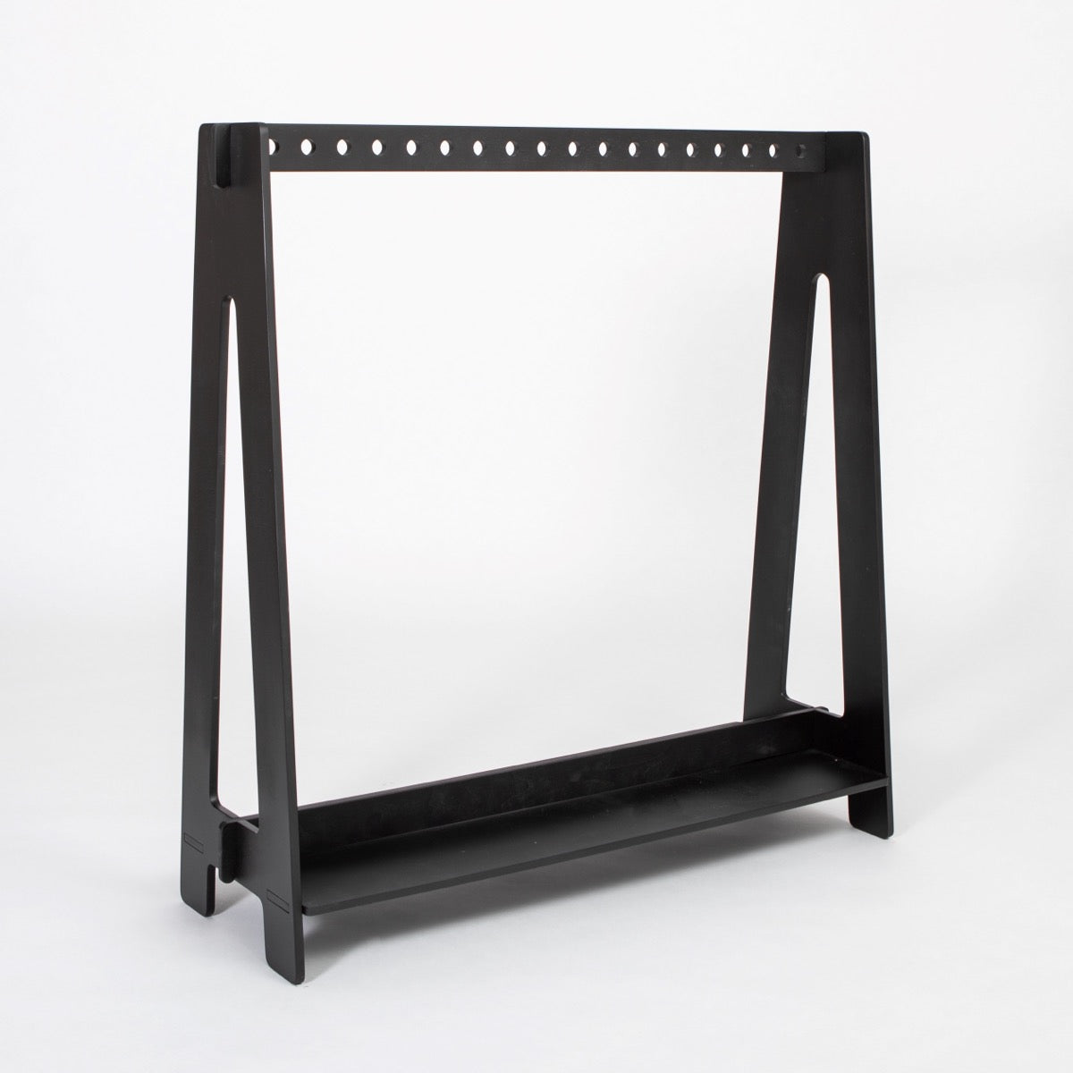 Black Montessori clothing rack with perforated rod and bottom shelf, side view