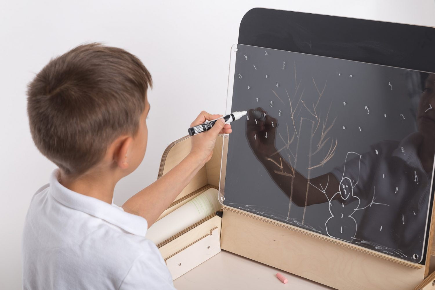 Child drawing on chalkboard surface of Montessori activity table