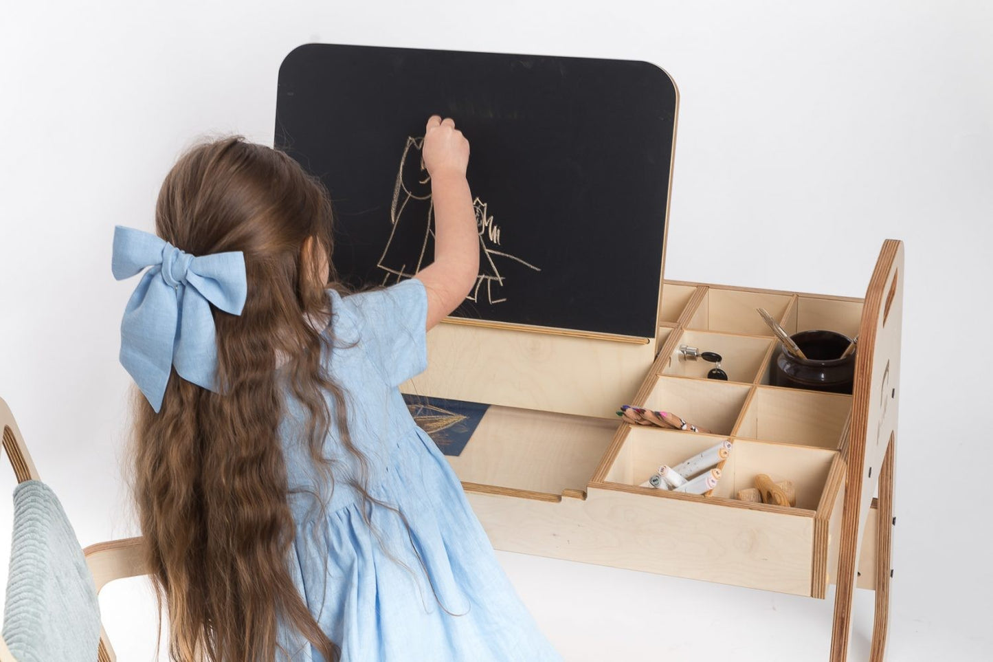 Child drawing on chalkboard surface of Montessori activity table