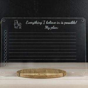 Chalkboard panel with inspirational text and wooden tray for chalk on table