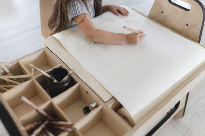 Child drawing on white paper using paper roll feature of Montessori table
