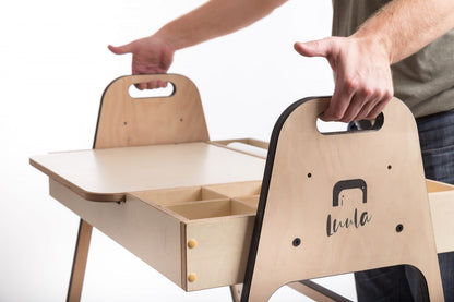 Two hands carrying cannon pink Montessori chair showing portable design and handles