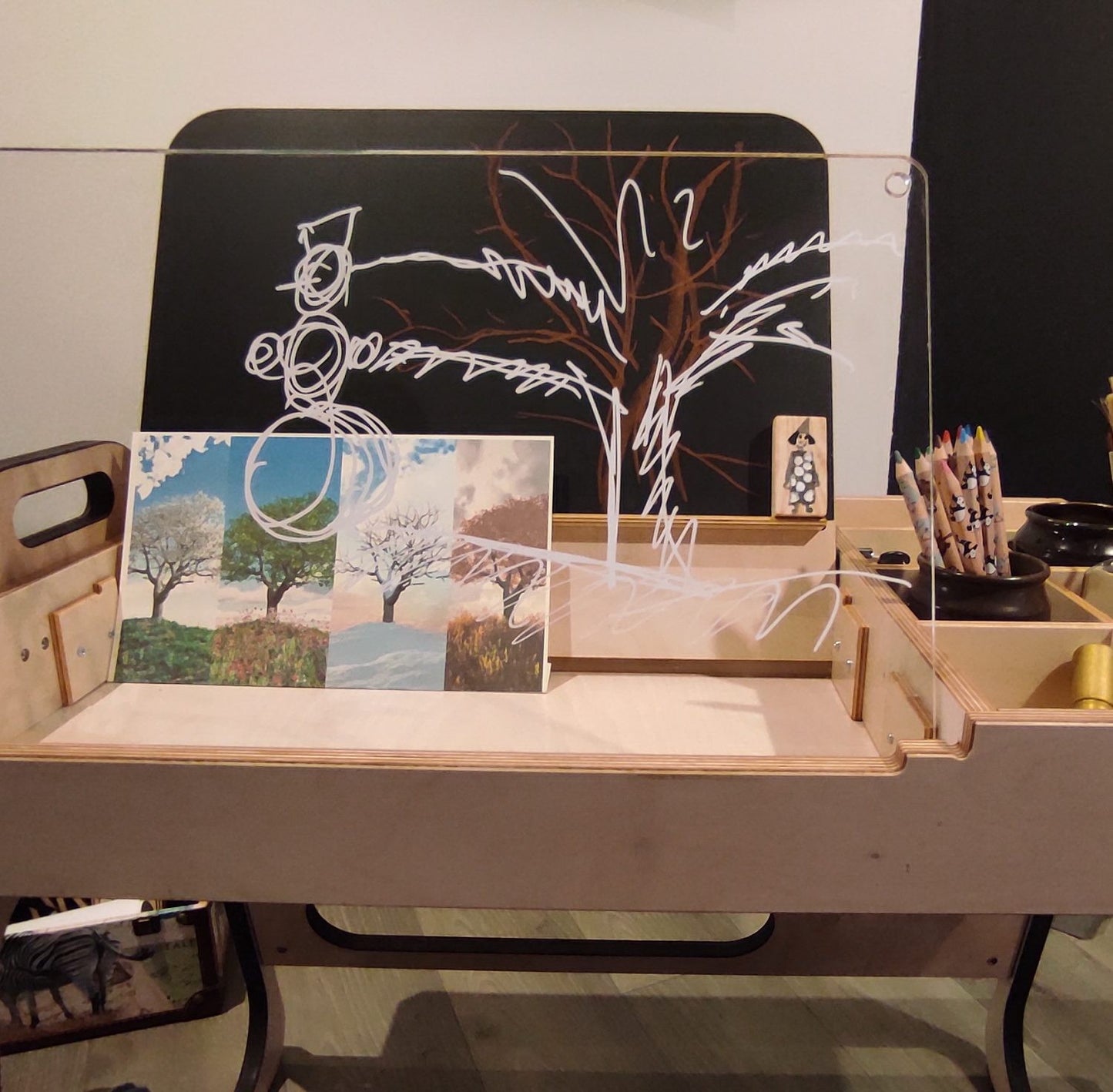 Montessori table workspace with blackboard, artwork display, and pencil storage