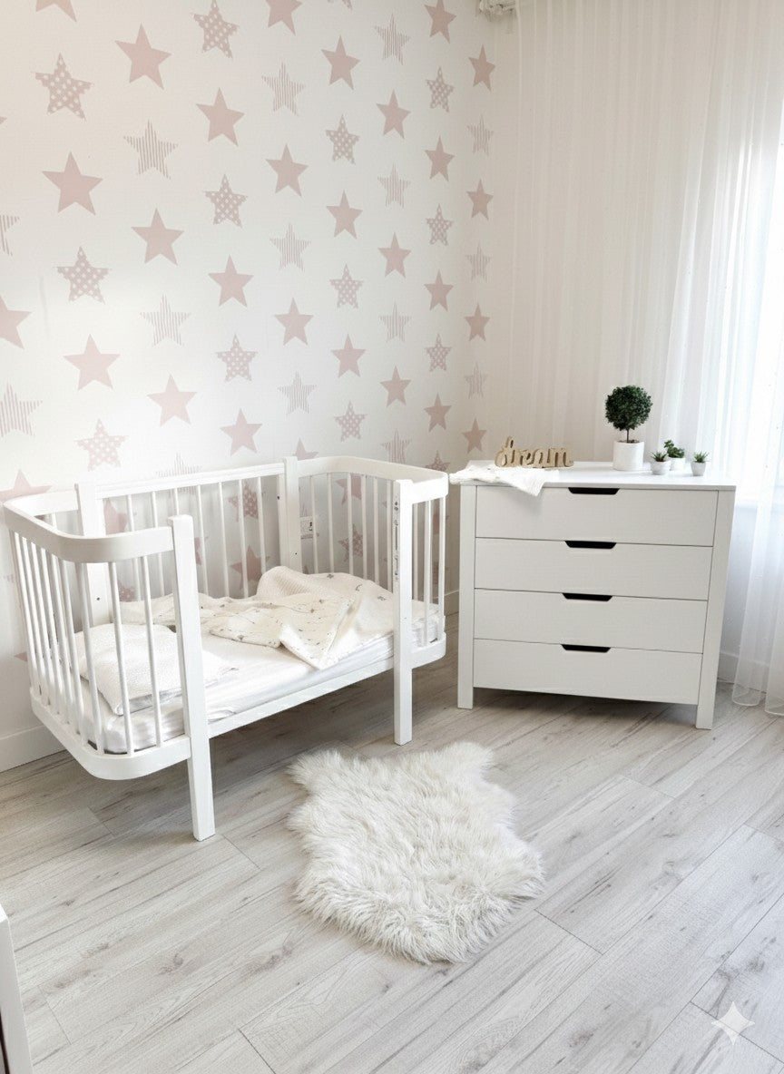 White KOTTO ELIN crib styled in modern nursery with star wallpaper and matching white dresser