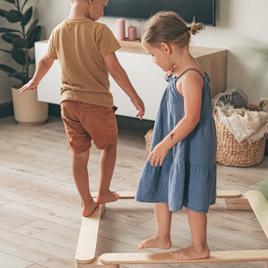 Two children balancing on wooden beams while playing indoors