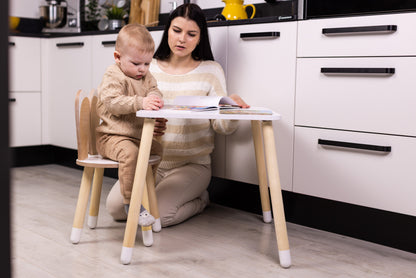 Toddler sitting in wooden bunny chair at table with adult nearby, showing chair size