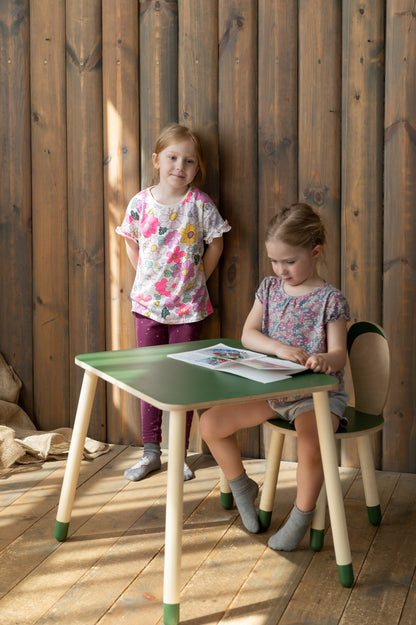 Two children using wooden bunny table with green top and matching chairs for crafts