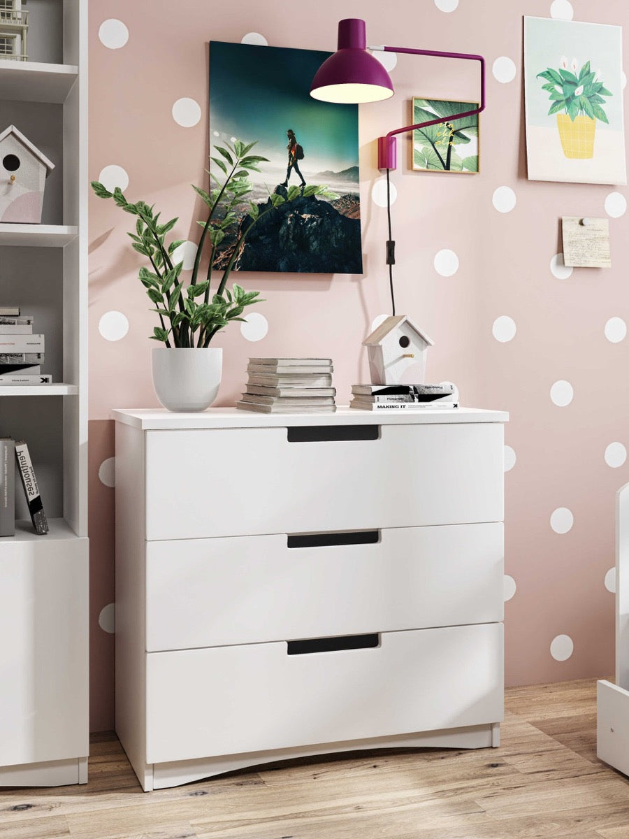 White classic chest of drawers in pink kids room with artwork and decorative accessories