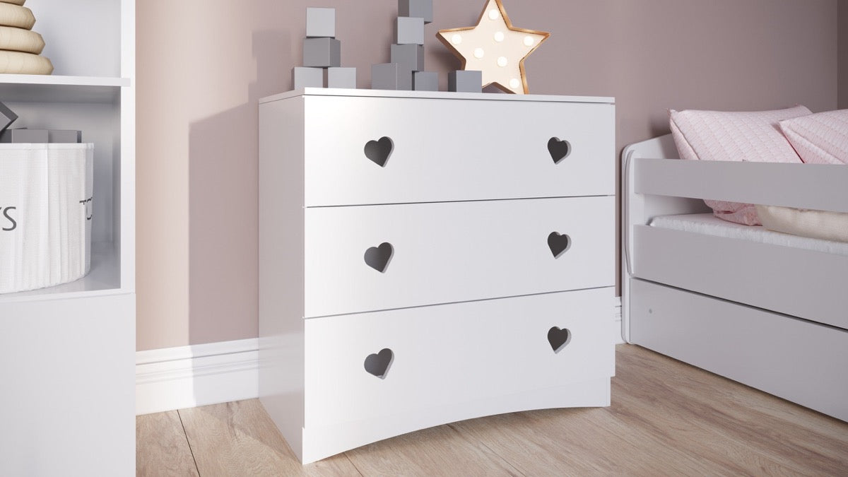 White kids chest of drawers with black heart-shaped handles in bedroom setting