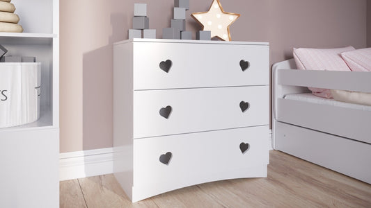 White kids chest of drawers with black heart-shaped handles in bedroom setting
