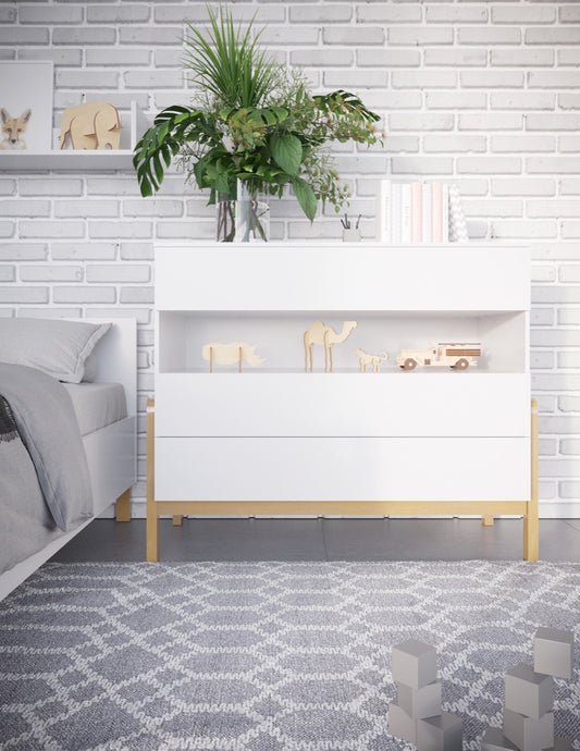 White Scandinavian chest of drawers with oak legs displayed in modern nursery next to bed