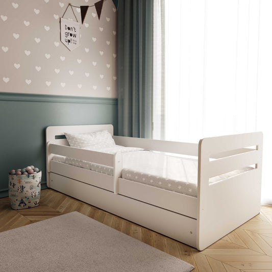 White Kocot Kids Tomi toddler bed with guardrail in bedroom setting