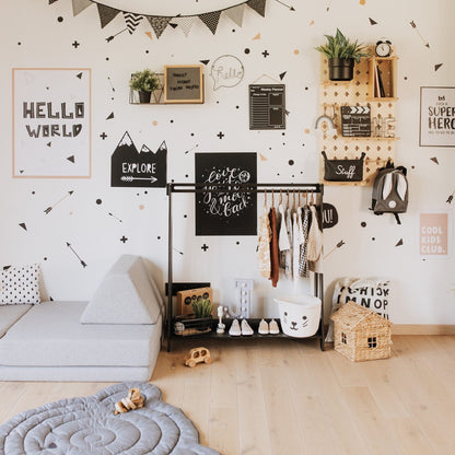 Black kids clothing rack holding colorful garments, styled in a playful bedroom accent wall setup
