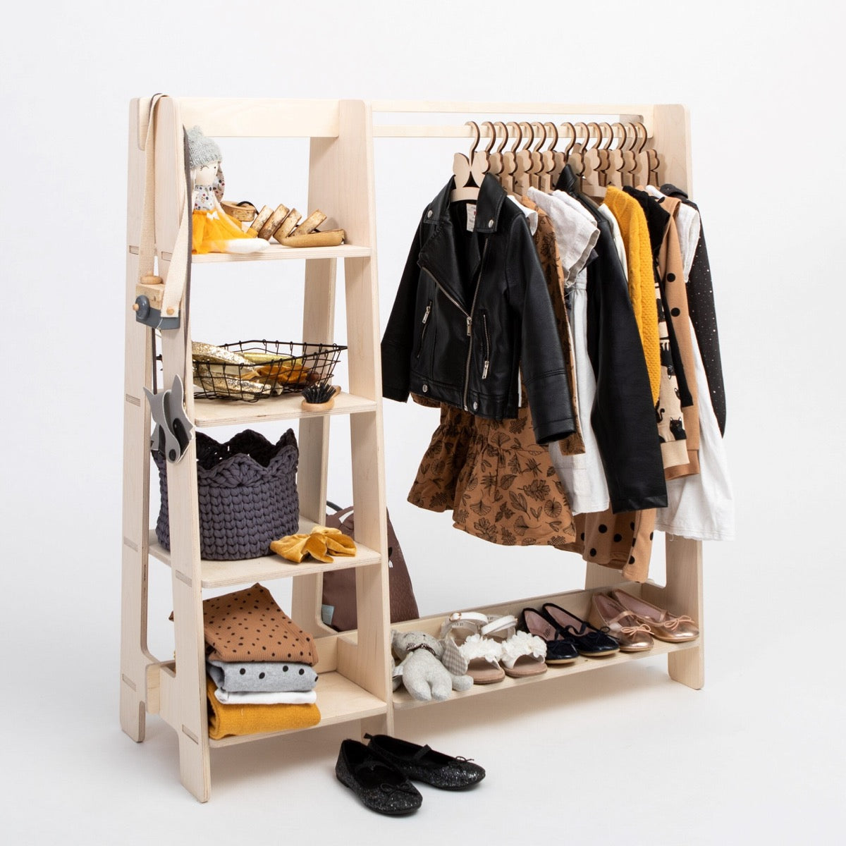 Natural birch wood kids wardrobe rack filled with colorful children's clothing and toys