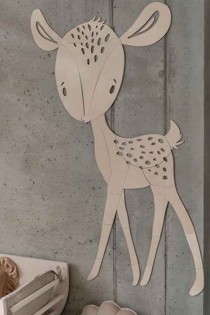 Wooden deer wall decoration with spotted coat and curved ears on concrete wall