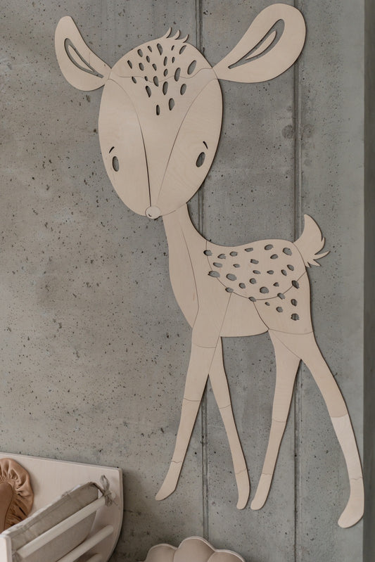 Wooden deer wall decoration with spotted coat and curved ears on concrete wall