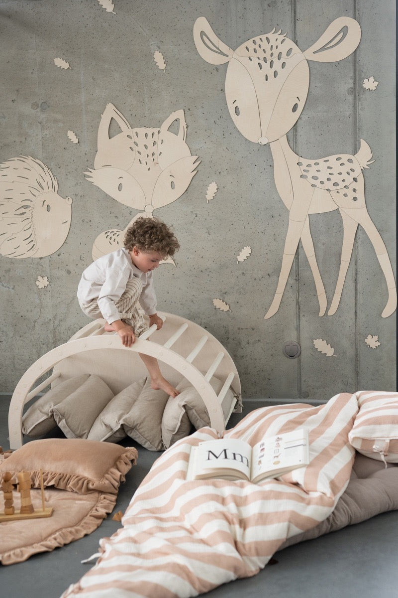 Child playing near wooden forest animal wall art with deer, fox, and hedgehog designs