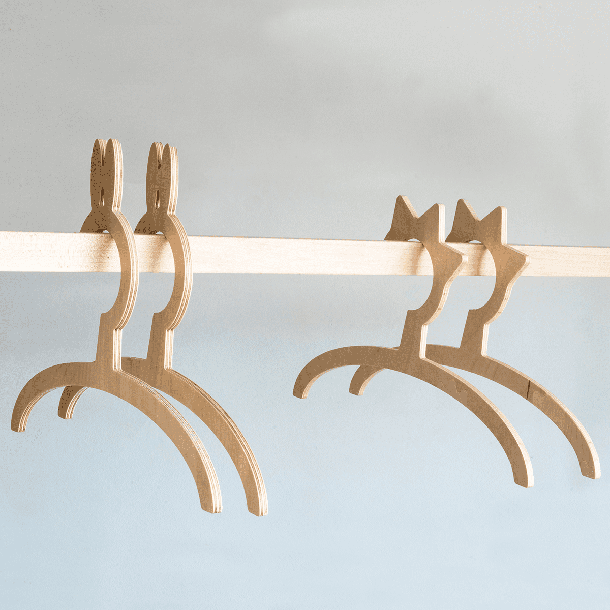 Four wooden child-sized hangers in natural finish designed for small clothes on the wardrobe