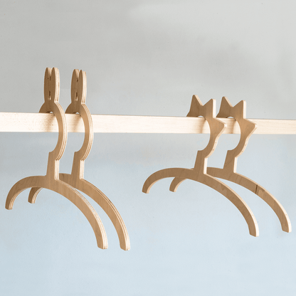 Four wooden child-sized hangers in natural finish designed for small clothes on the wardrobe