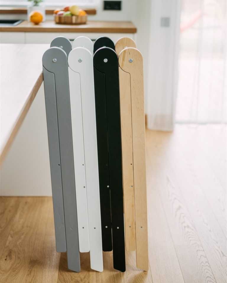 Four color variants of foldable kitchen tower displayed side by side in grey, white, black, and natural wood