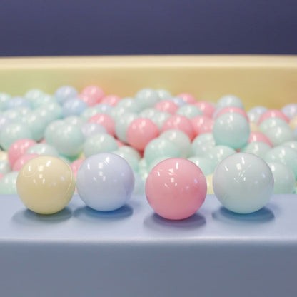 Close-up of pastel ball pit balls showing pink, blue, cream, and lavender soft plastic balls with glossy finish