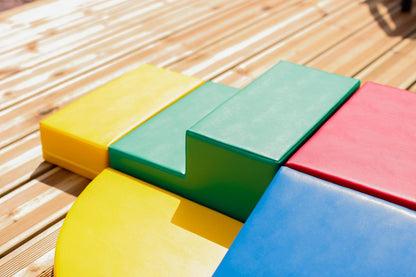 Colorful foam blocks in yellow, green, pink and blue arranged on wooden deck