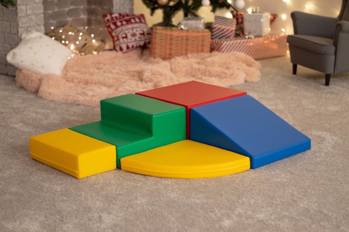 Soft foam climbing blocks arranged indoors on beige carpet near holiday decorations