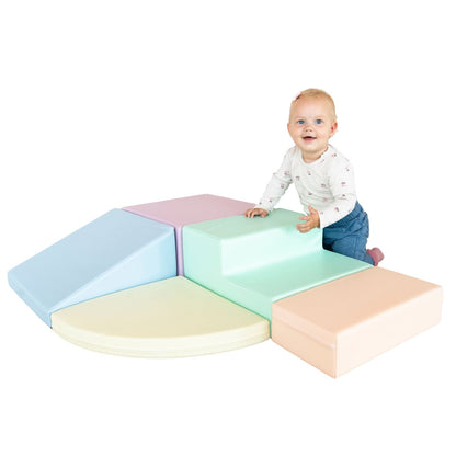 Child crawling across light pastel foam blocks arranged as corner climber