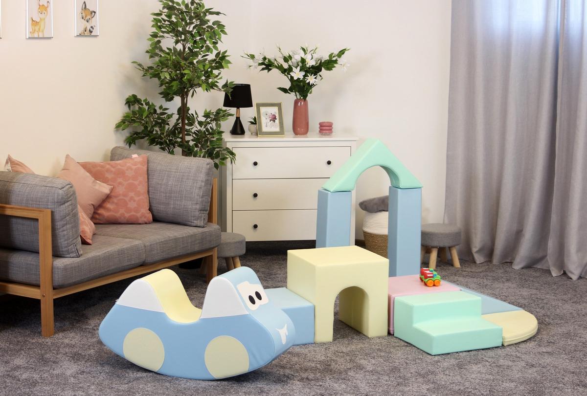Toddler crawling over blue foam blocks with colorful IGLU soft play shapes in living room