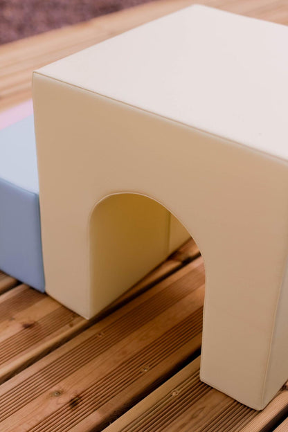 Close-up of cream-colored foam block with curved tunnel opening on wooden surface