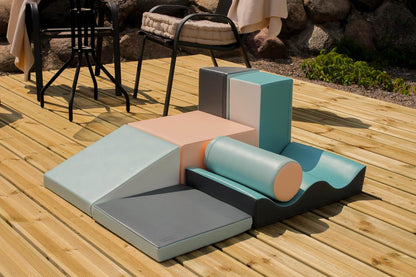 Soft foam climbing blocks with ramp and curved pieces on sunny wooden deck