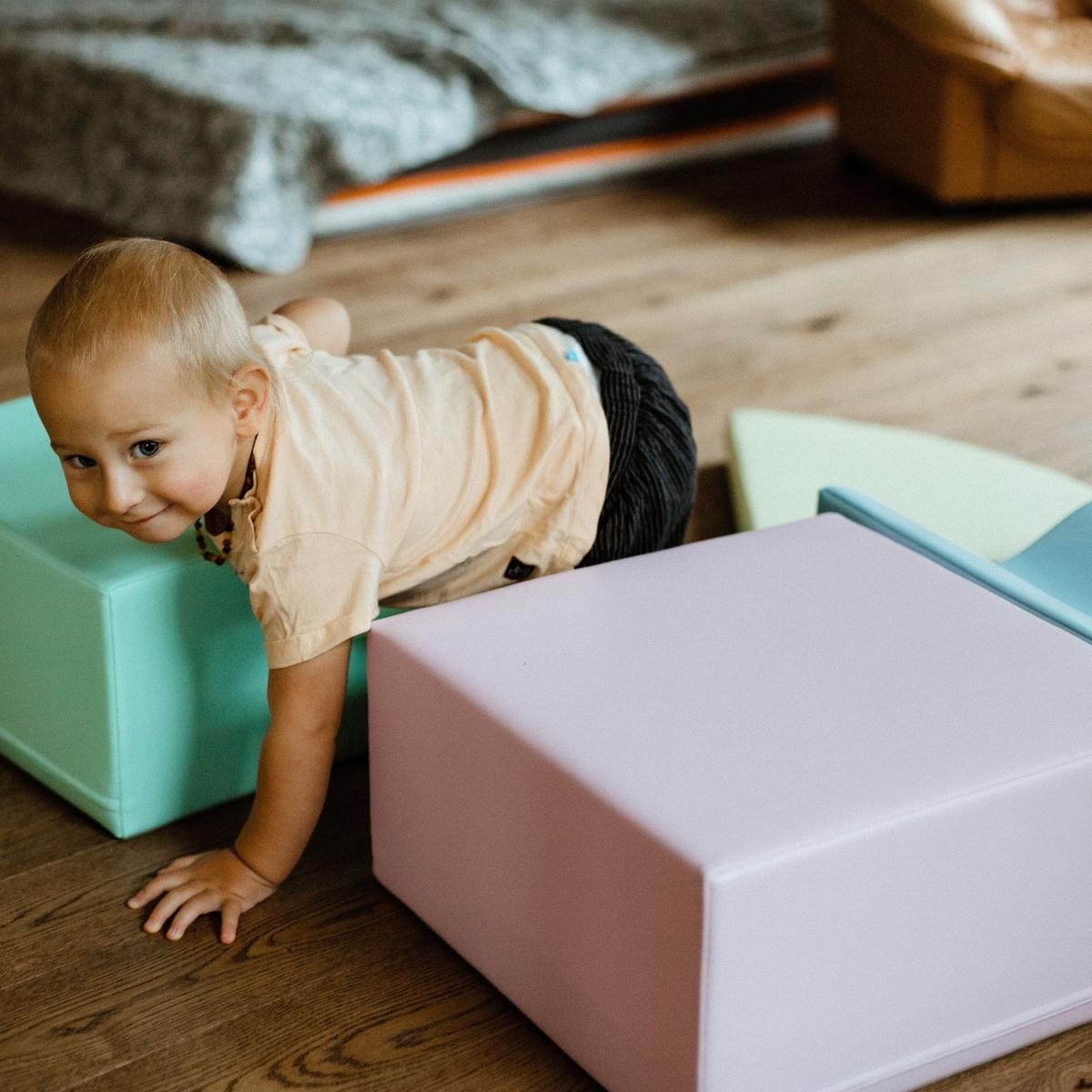 Toddler crawling under cream foam cylinder on pink and blue foam blocks