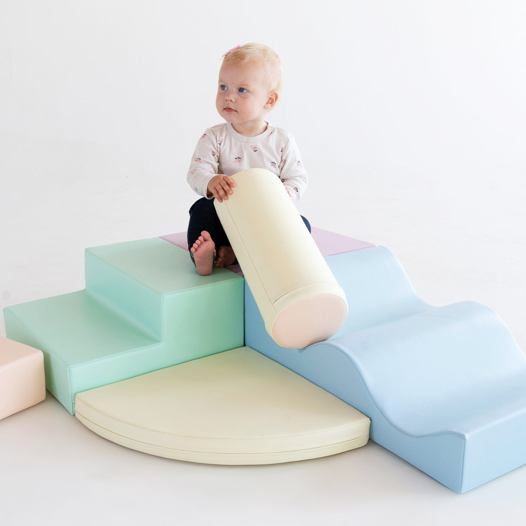 Two toddlers interacting with light pastel foam blocks arranged as play structure