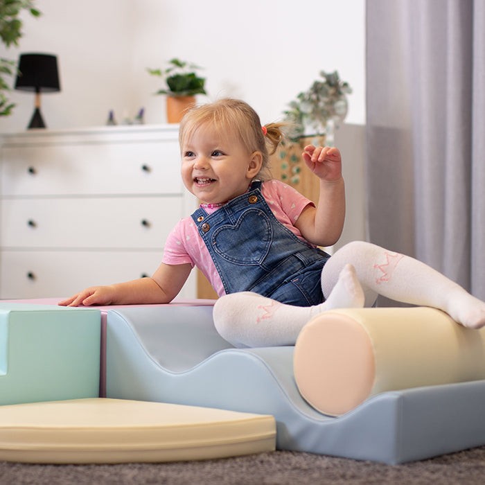 Toddler at rest on assembled light pastel foam block and ramp structure