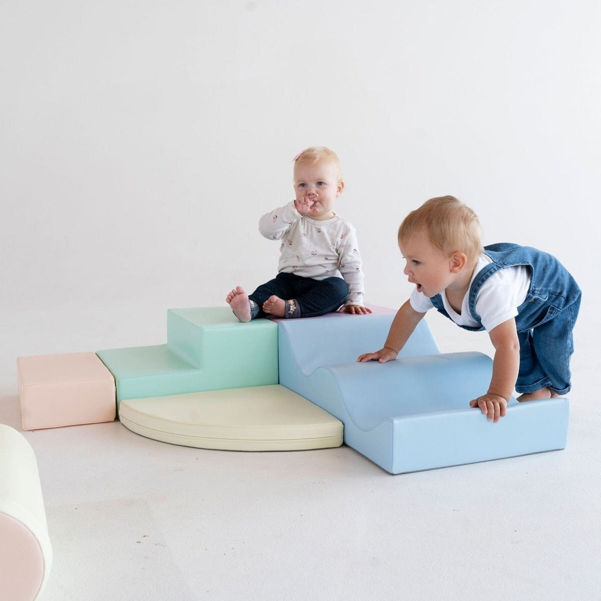 Toddler climbing on assembled light pastel foam block structure