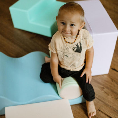 Toddler standing beside tall stacked light pastel foam block tower