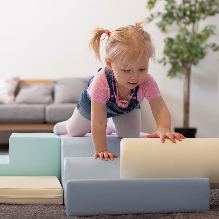 Two toddlers standing beside tall light pastel foam block tower structure