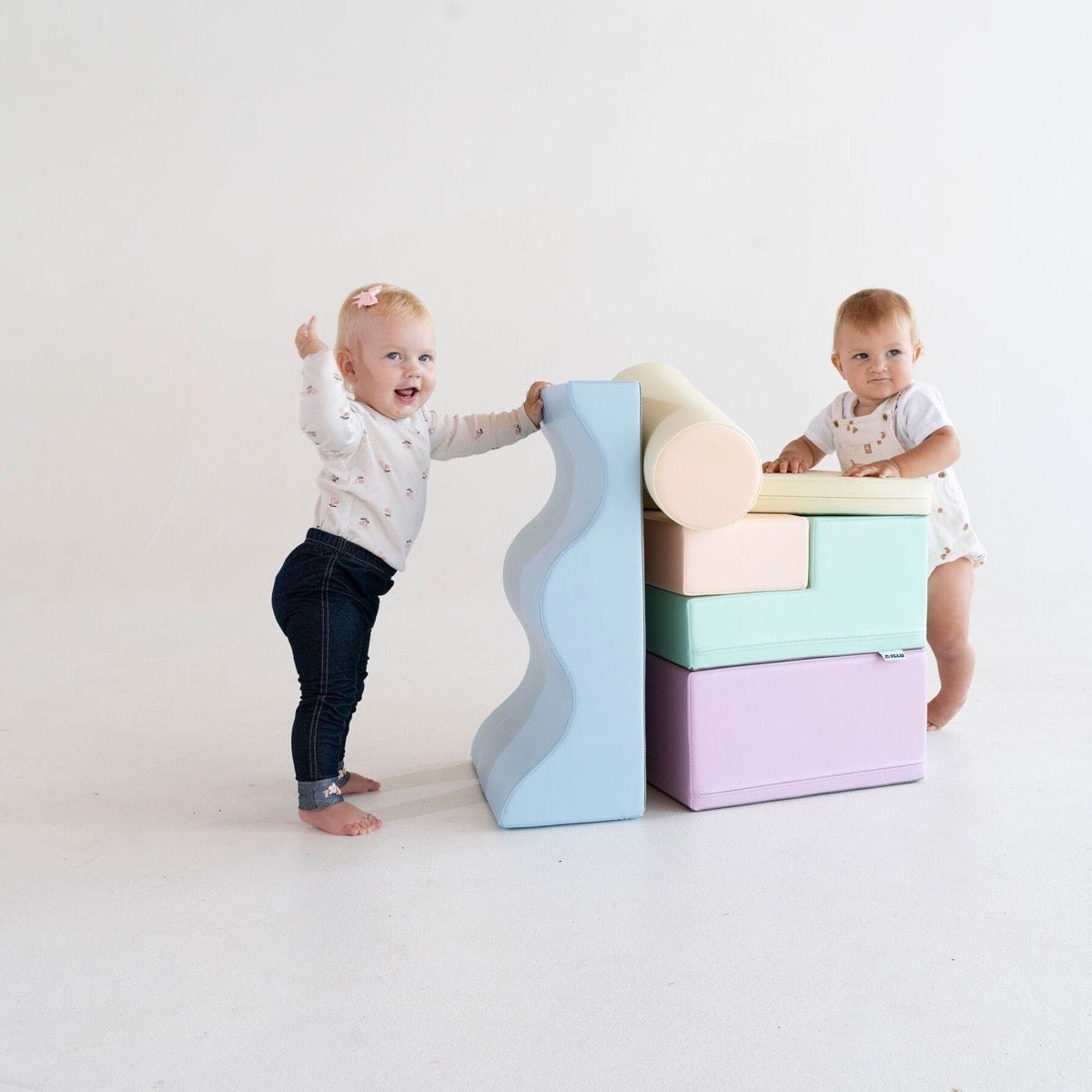 Toddler crawling on light pastel foam block structure in modern playroom